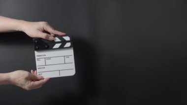 Klasik bir film sehpası ya da film tahtası tutuluyor ve karanlık bir arkaplana çarpılıyor. Eğlence sektöründe film yapımcılığı, film çekimi ve yaratıcı hikaye anlatımını sembolize eder..