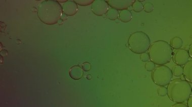 Petrol baloncukları soyut arka planda hareket eder. Renk sıvısı içinde yüzen berrak yağ kabarcıklarının hareketi. Rahatlatıcı ve sanatsal görsel deneyim. Petrol ve sudan akıcılık bilimini sembolize ediyor.