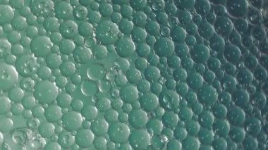 Petrol baloncukları soyut arka planda hareket eder. Renk sıvısı içinde yüzen berrak yağ kabarcıklarının hareketi. Rahatlatıcı ve sanatsal görsel deneyim. Petrol ve sudan akıcılık bilimini sembolize ediyor.