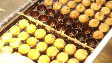 Japon Takoyaki yemekleri. Bir sokak yemeği şefi taze pişmiş takoyaki hazırlıyor. Japonya Takoyaki içi doğranmış ahtapotla dolu hamurdan yapıldı ve sıcak servis edildi. Şef altın Tako toplarını tepsiye koyar..