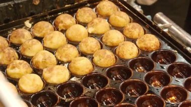 Japon Takoyaki yemekleri. Bir sokak yemeği şefi taze pişmiş takoyaki hazırlıyor. Japonya Takoyaki içi doğranmış ahtapotla dolu hamurdan yapıldı ve sıcak servis edildi. Şef altın Tako toplarını tepsiye koyar..