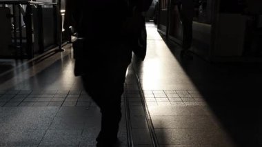 Gün batımına karşı yürüyen kalabalığın silueti. İşten sonra tren istasyonunda altın bir gün batımında yürüyen meşgul yayaların gölgeleri. Gece atmosferinin uzun gölgeleri ve sıcak ışıkları.