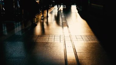 Gün batımına karşı yürüyen kalabalığın silueti. İşten sonra tren istasyonunda altın bir gün batımında yürüyen meşgul yayaların gölgeleri. Gece atmosferinin uzun gölgeleri ve sıcak ışıkları.