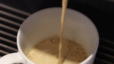 Kahve dolduruyorum. Beyaz bardağa dökülen yeni demlenmiş kahvenin yavaş çekimini kapat. Yumuşak köpüklü yüzey. Sıcak Americano ya da Espresso kahvesi. Kahve için kahve fincanındaki zengin aroma..