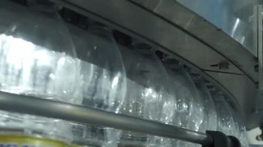Fabrikadaki plastik şişe üretim hattının yakın görüntüsü. Şeffaf PET şişelerinin bir kısmı otomatik taşıma sistemi boyunca hareket ediyor. Modern PET içecek şişelerinin otomasyon ürettiğini gösteriyor..