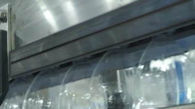Fabrikadaki plastik şişe üretim hattının yakın görüntüsü. Şeffaf PET şişelerinin bir kısmı otomatik taşıma sistemi boyunca hareket ediyor. Modern PET içecek şişelerinin otomasyon ürettiğini gösteriyor..