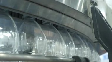 Fabrikadaki plastik şişe üretim hattının yakın görüntüsü. Şeffaf PET şişelerinin bir kısmı otomatik taşıma sistemi boyunca hareket ediyor. Modern PET içecek şişelerinin otomasyon ürettiğini gösteriyor..