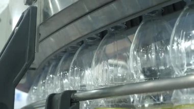 Fabrikadaki plastik şişe üretim hattının yakın görüntüsü. Şeffaf PET şişelerinin bir kısmı otomatik taşıma sistemi boyunca hareket ediyor. Modern PET içecek şişelerinin otomasyon ürettiğini gösteriyor..