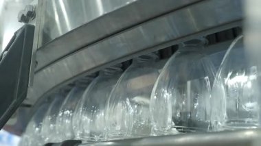 Fabrikadaki plastik şişe üretim hattının yakın görüntüsü. Şeffaf PET şişelerinin bir kısmı otomatik taşıma sistemi boyunca hareket ediyor. Modern PET içecek şişelerinin otomasyon ürettiğini gösteriyor..