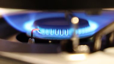 Gaz ocağı alevi. Gaz sobasını kapat ve mavi bir ateşle tutuştur. Ateşleme elektrodu, ateşi yakarken kırmızı bir şekilde parlar. Mutfak gaz sobasında kontrollü yanma sürecini gösterir.