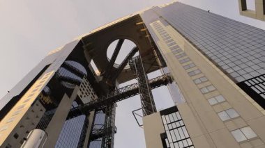 Osaka 'daki Umeda Gökyüzü Binası ve akşamları güneş ışığı. Şehir simgesi, tepesinde ikiz kuleleri birbirine bağlayan eşsiz bir yüzen bahçe gözlemevi barındırıyor. Umeda Gökyüzü Binası Osaka Tarihi Yerleşim yerlerinden biri.
