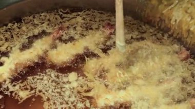 Karides tempura. Sıcak yağda kızartılmış karides tempurasına yakın çekim. Tong köpüren tavadan çıtır çıtır bir parça kaldırıyor. Altın hamuru kıtır kıtır kıtır kıtır yapar. Kızarmış tempura Osaka Japonya.