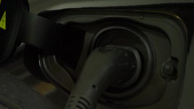 Elektrikli araç ya da EV araba istasyonda şarj oluyor. Aktif güç akışı gösteren parlayan bir ışık göstergesi ile. EV Temiz Enerji Çözümü. Sürdürülebilir ulaşım, çevre dostu hareketliliğin geleceği.