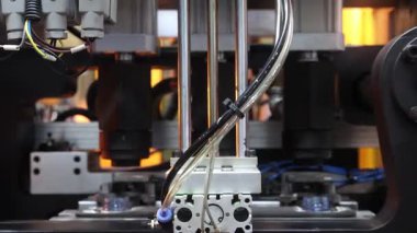 Endüstriyel üretim makinesindeki plastik PET şişesinin ısıtma işlemini kapat. Otomatik endüstriyel PET şişe makinesi. Yüksek hızlı plastik şişe üretiminde robot sistem otomasyonu.