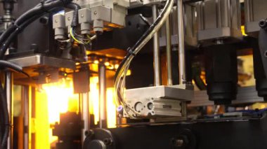 Endüstriyel üretim makinesindeki plastik PET şişesinin ısıtma işlemini kapat. Otomatik endüstriyel PET şişe makinesi. Yüksek hızlı plastik şişe üretiminde robot sistem otomasyonu.