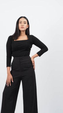 Şık siyah kıyafetli şık bir manken stüdyoda güven içinde poz veriyor. Kadın, zamansız stil ve modern yetenekle profesyonel giysiler sergiliyor. Moda ve yaşam tarzı kavramları için ideal