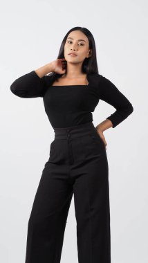 Şık siyah kıyafetli şık bir manken stüdyoda güven içinde poz veriyor. Kadın, zamansız stil ve modern yetenekle profesyonel giysiler sergiliyor. Moda ve yaşam tarzı kavramları için ideal