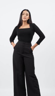 Şık siyah kıyafetli şık bir manken stüdyoda güven içinde poz veriyor. Kadın, zamansız stil ve modern yetenekle profesyonel giysiler sergiliyor. Moda ve yaşam tarzı kavramları için ideal