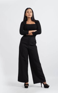 Şık siyah kıyafetli şık bir manken stüdyoda güven içinde poz veriyor. Kadın, zamansız stil ve modern yetenekle profesyonel giysiler sergiliyor. Moda ve yaşam tarzı kavramları için ideal