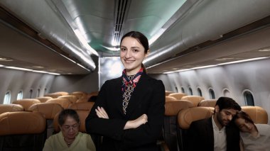 Hostes. Üniformalı gülen uçuş görevlisi modern bir uçağa binen yolcuları karşılıyor ve onlara rehberlik ediyor. Arkadaş canlısı havayolu personeli profesyonel hizmet ve konforlu uçuş deneyimi sunuyor