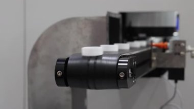 Plastik kapak yapımı. Modern fabrikadaki otomatik montaj makinesinde hareket eden plastik kapsüllerin tanıtımı. Endüstriyel plastik ambalaj ve şişe kapağı imalatında hassas mühendislik ve robotik.