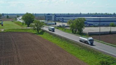 Kamyonlar güneşli bir günde otoyol boyunca araba sürer. Hava takibi atışı. 4K video