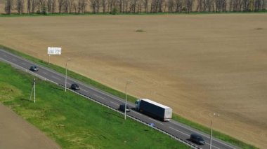 Kamyonlar güneşli bir günde otoyol boyunca araba sürer. Hava takibi atışı. 4K video