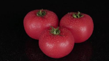 Domatesler siyah arkaplanda, dönen masa. Sağlıklı vejetaryen yemekleri