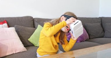 6 yaşında bir çocuk evde kahverengi bir koltukta oturup sanal gerçeklik gözlükleriyle 360 video izliyor.