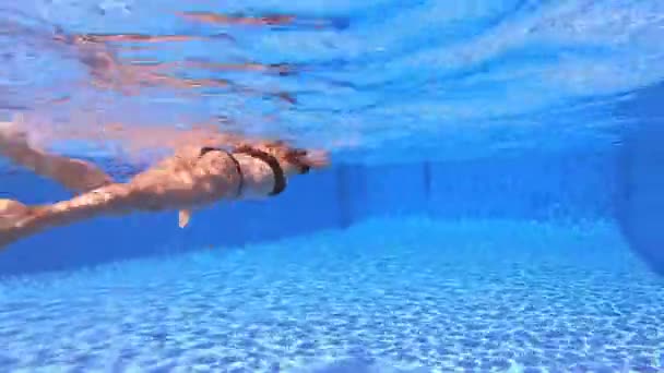在清澈的池水中 红头发女人穿着黑色比基尼游泳爬泳风格后的水下景观 — 图库视频影像