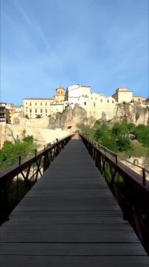 Cuenca 'daki tarihi demir köprü boyunca Casas Colgadas ve San Pablo Manastırı ile birlikte Cuenca, Castilla La Mancha, İspanya' da yürüyün. Dikey video. Görüş Noktası (POV), öznel görünüm