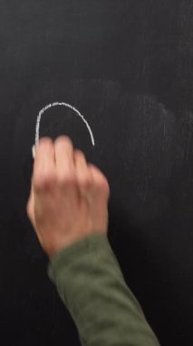 Bir el siyah tahtaya beyaz tebeşirli bir kalp çizer. Dikey video