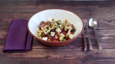 Kırsal seramik kâse. Kaşık, çatal ve bıçaklı kinoa salatası ve ahşap bir masanın üzerinde mor bir peçete.