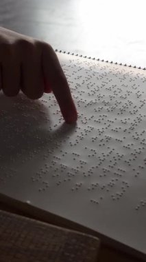 Körler dilinde kitap okuyan bir kızın parmağı: körler alfabesi. Dikey video