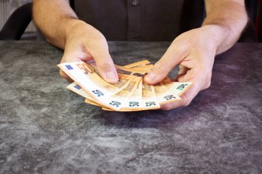 50 Euro 'luk banknotları dokulu bir masada gösteren erkek elleri.