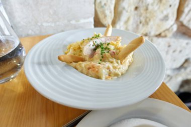 Rus salatası denilen tipik İspanyol tapası, haşlanmış patates ve yumurta, havuç, bezelye, mayonez, ton balığı göbeği, doğranmış soğan ve ekmek çubuklarını bir restorandaki ahşap bir masada beyaz bir tabakta.