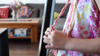 Evinin oturma odasında bir tutam saçı renkli iplikle ören bir kızın ellerini kapat.