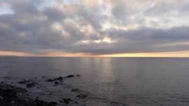 Akdeniz ufkunun suyunun üzerinde mavi saatte bulutlu güzel şafak vakti. Gökyüzündeki bulutlar ve okyanus dalgaları hızla hareket ediyor.