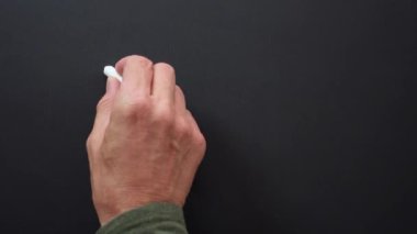 Bir el siyah tahtaya beyaz tebeşirle nakit kelimesini yazar.