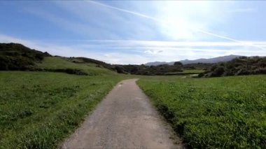 Llanes, Asturias, İspanya 'daki yeşil çimenlerin arasında toprak bir yolda yürüyorum. Görüş Noktası (POV), öznel görünüm