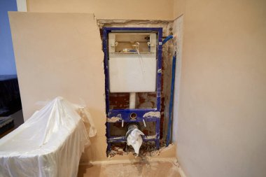 İnşaat halindeki duvar, bir banyonun iç sarnıçlarını korumak için plastikle kaplı bir evde gösteriyor.