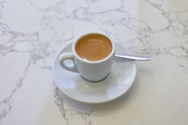 Beyaz seramik bardakta servis edilen klasik bir espresso. Zengin kahve mermer yüzeyle çok güzel zıtlaşıyor, basit, zarif bir kahve anının özünü yakalıyor.