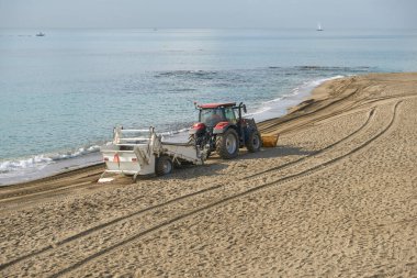 Sahil temizleme traktörü, deniz kenarında kumlu bir kıyı şeridinde sakin bir Akdeniz ile birlikte. Benalmadena, Malaga, Endülüs, İspanya