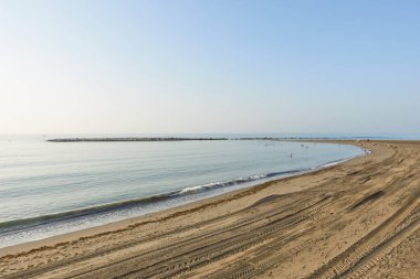 Yumuşak dalgaları olan sakin bir sahil, kumda lastik izleri ve açık mavi gökyüzünün altında dalgalanan bir su ve Akdeniz 'deki ufuk. Benalmadena Costa, Malaga, Endülüs, İspanya