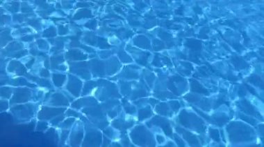 Sakin, berrak bir havuz. Dalgalanmalar mavi suya güneş ışığını yansıtıyor. Büyüleyici desenler yaratıyor. Akışkanlık ve ışık yansımaları bir yaz gününün dingin ve ferahlatıcı atmosferini vurgular.