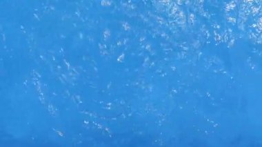 Güneş ışığını yansıtan dalgalarla püskürtücü jetin etkisiyle havuzun yüzeyinde suyun hareketi