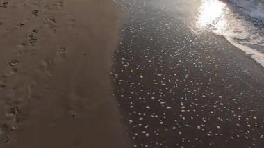 Denizin dalgalarının ulaştığı kumsalda yürüyorum.