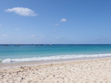Atlantik Okyanusu 'ndaki tekneler ve beyaz dalgalar Afrika' daki Santa Maria kasabasında Cape Verde 'deki Sal Adası' nda, 2019 'da güneşli bir bahar gününde açık mavi gökyüzü.