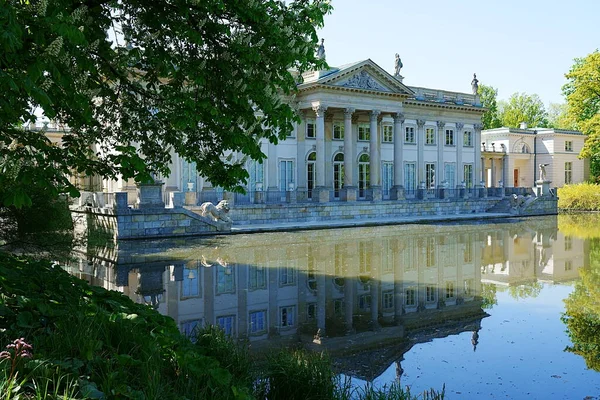 Palace on isle reflected in water in Warsaw european capital city of Poland, clear blue sky in 2022 warm sunny spring day on May.