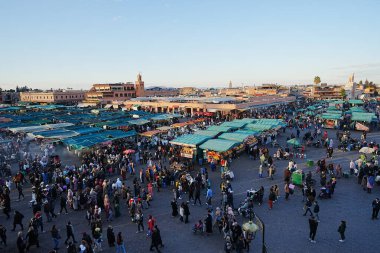 MARRAKESH, MOROCCO - 28 HAZİRAN 2023: Afrika şehrindeki Jemaa el-Fnaa 'daki insanlar, ılık güneşli kış gününde açık mavi gökyüzü.